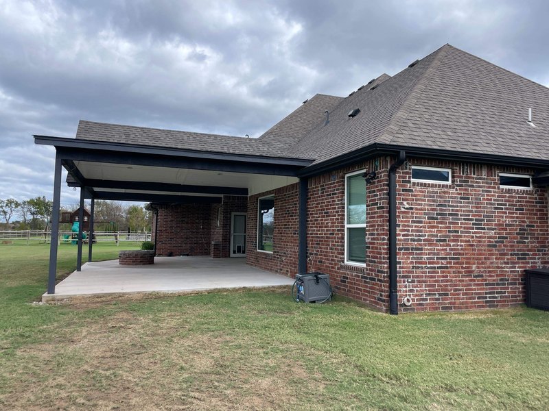 Dark bronze gutters and downspouts on a red brick home with a dark shingle roof