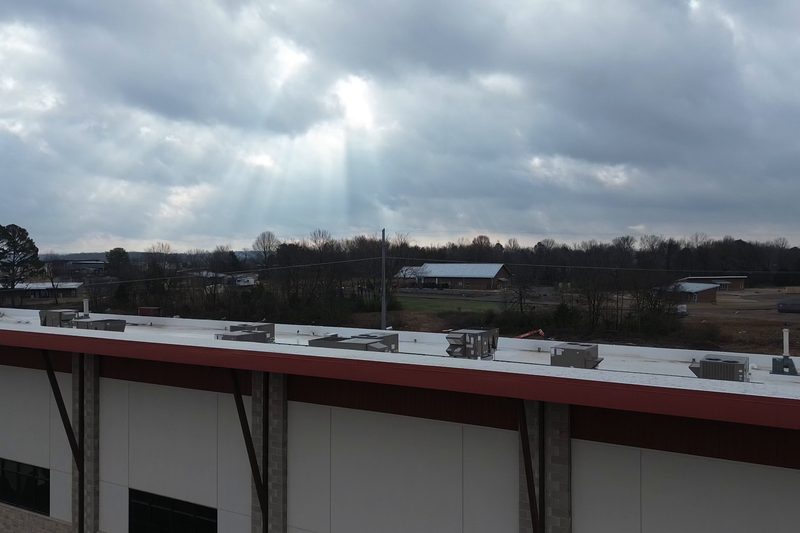 Flat commercial roof with a red parapet under dramatic storm clouds
