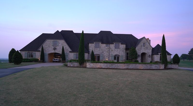 Large stone home at dusk with a premium shingle roof