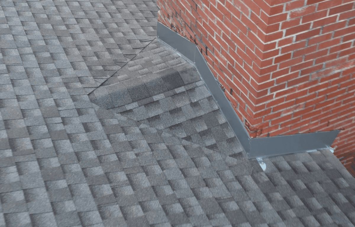 New metal apron and step flashing where a shingle roof meets a brick chimney