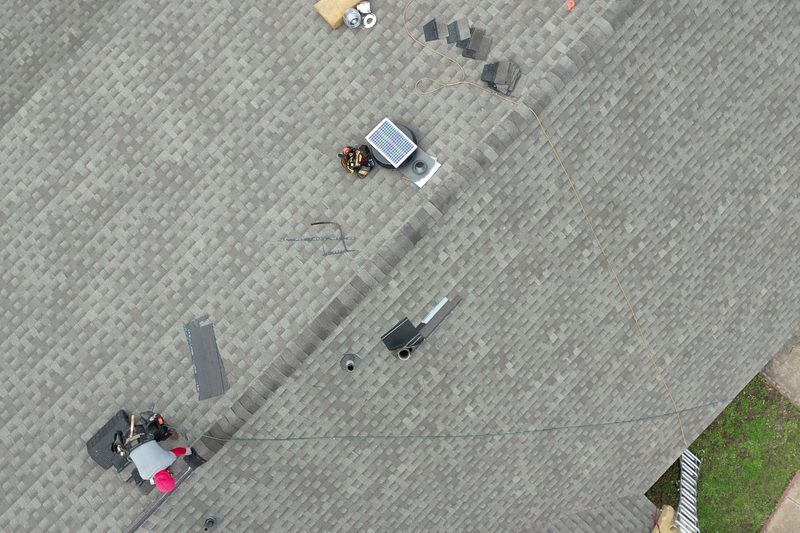 Overhead view of a shingle roof with tools and materials during a repair