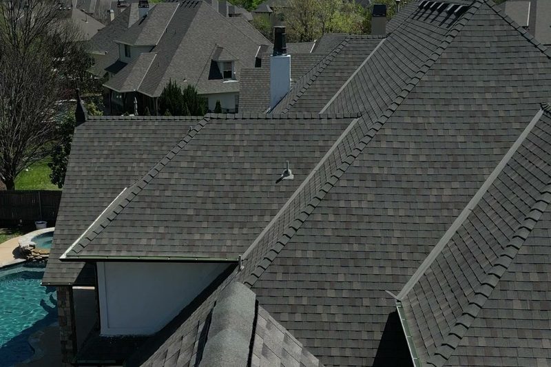 Aerial view of a weathered dark shingle roof on a Tulsa-area home