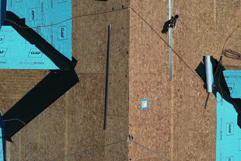 Overhead view of new decking and underlayment going on during a roof replacement