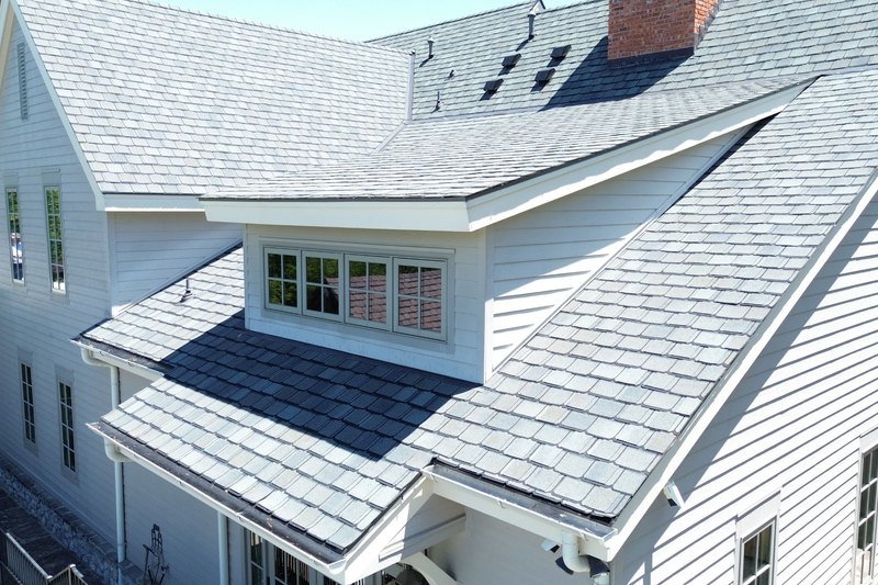 Steep two-story roof with dormers and several roof planes on a white-sided home