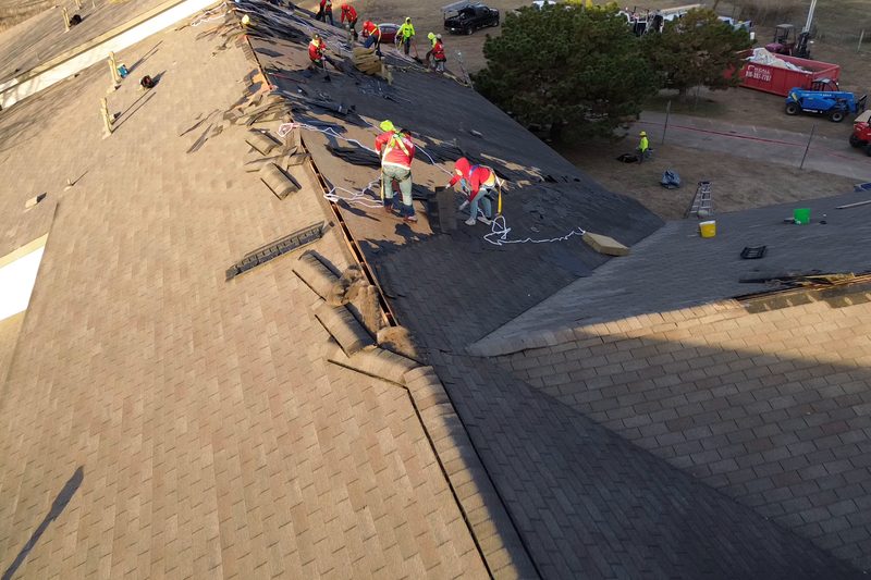 RainTech crew installing new shingles on a roof, with shingle bundles staged along the slope