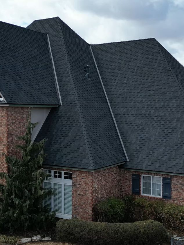 Brick home with a new dark shingle roof installed by RainTech