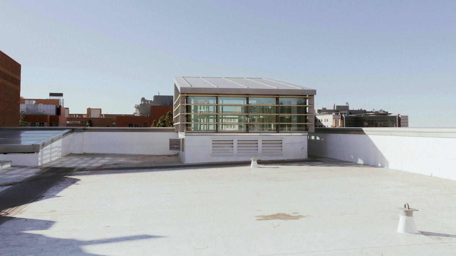 Flat commercial roof with a white restoration coating, parapet walls and rooftop penthouse