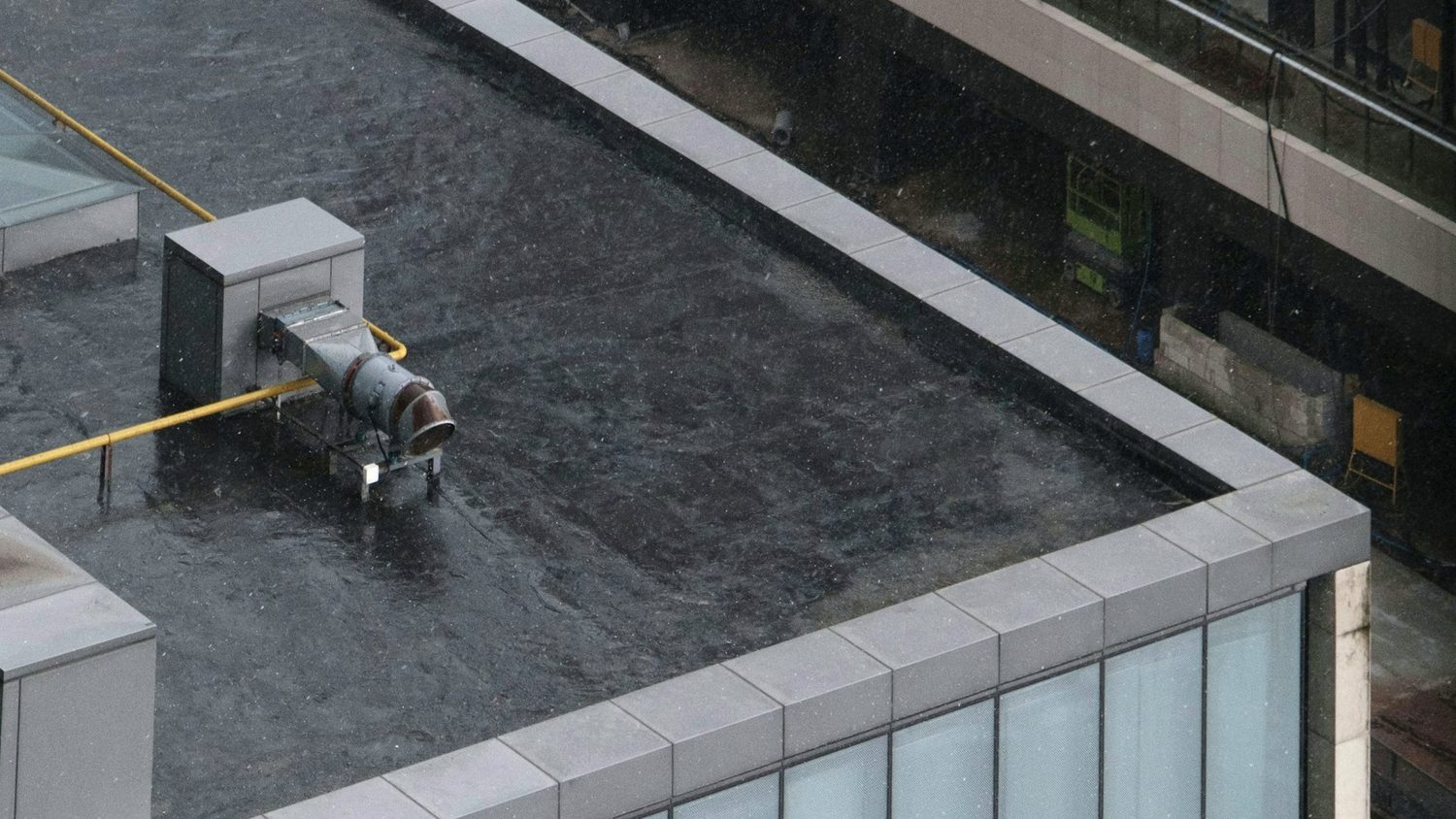 Black EPDM membrane on a flat commercial roof with metal coping and rooftop equipment