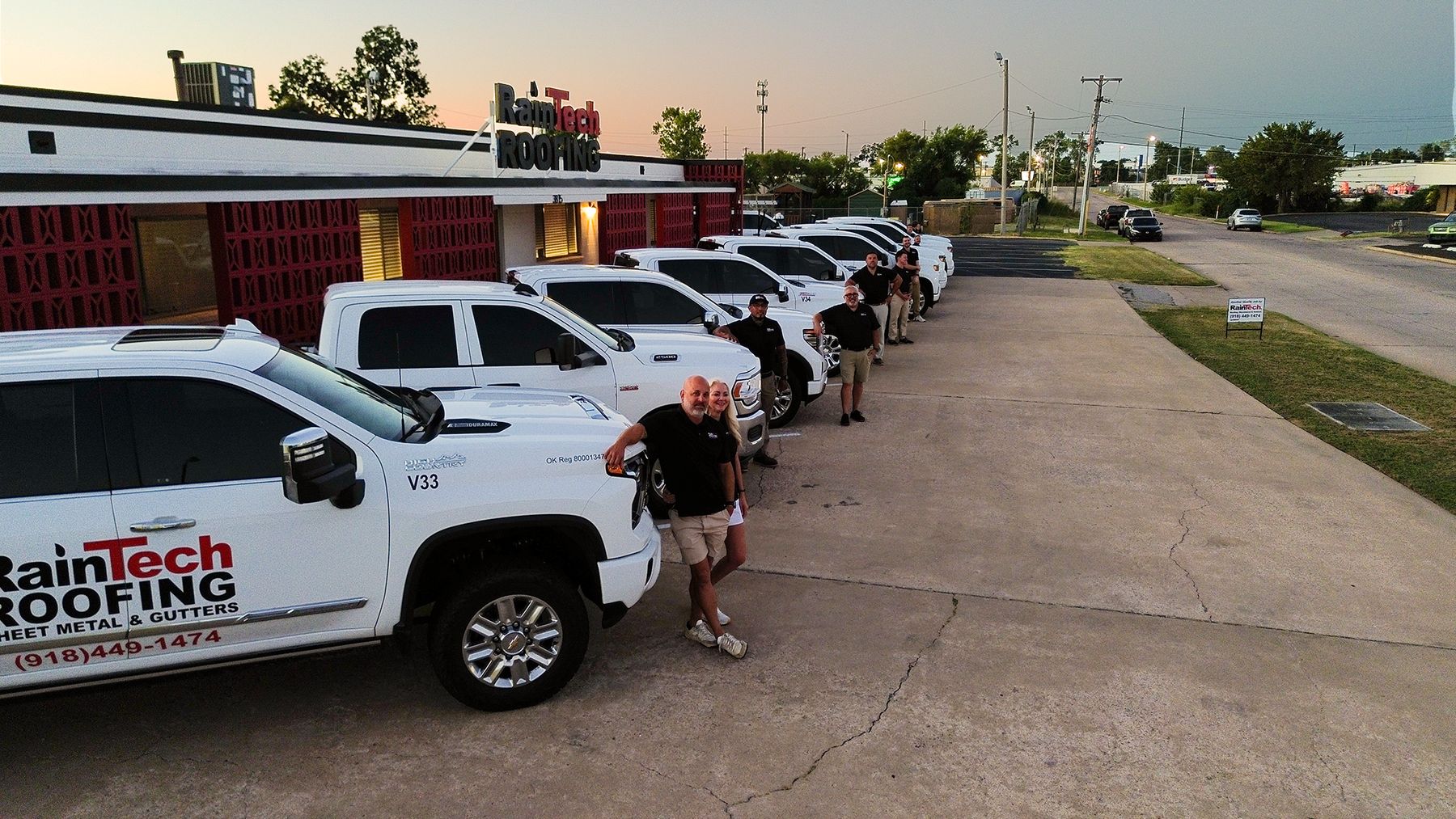 The RainTech Roofing team with their trucks outside the Tulsa headquarters at sunset