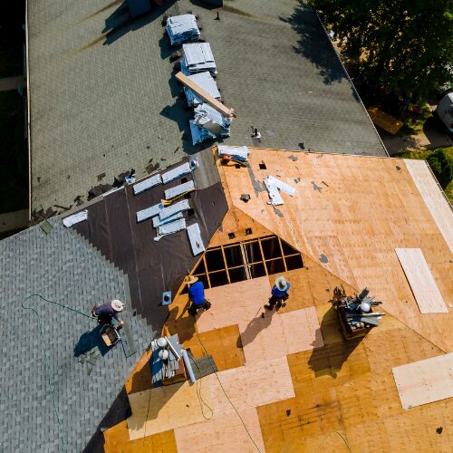 Team installing new asphalt shingle roofing on a commercial building in Tulsa