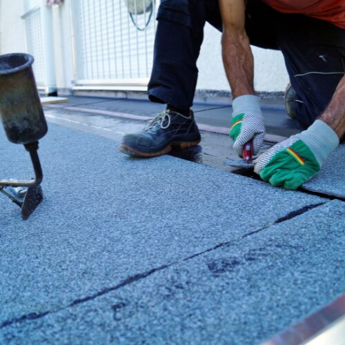 A roofing contractor applying modified bitumen to a commercial building.